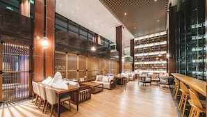A spacious lobby with wooden flooring, seating areas, and a large bookshelf. - Le Méridien Emei Mountain Resort (Leshan)