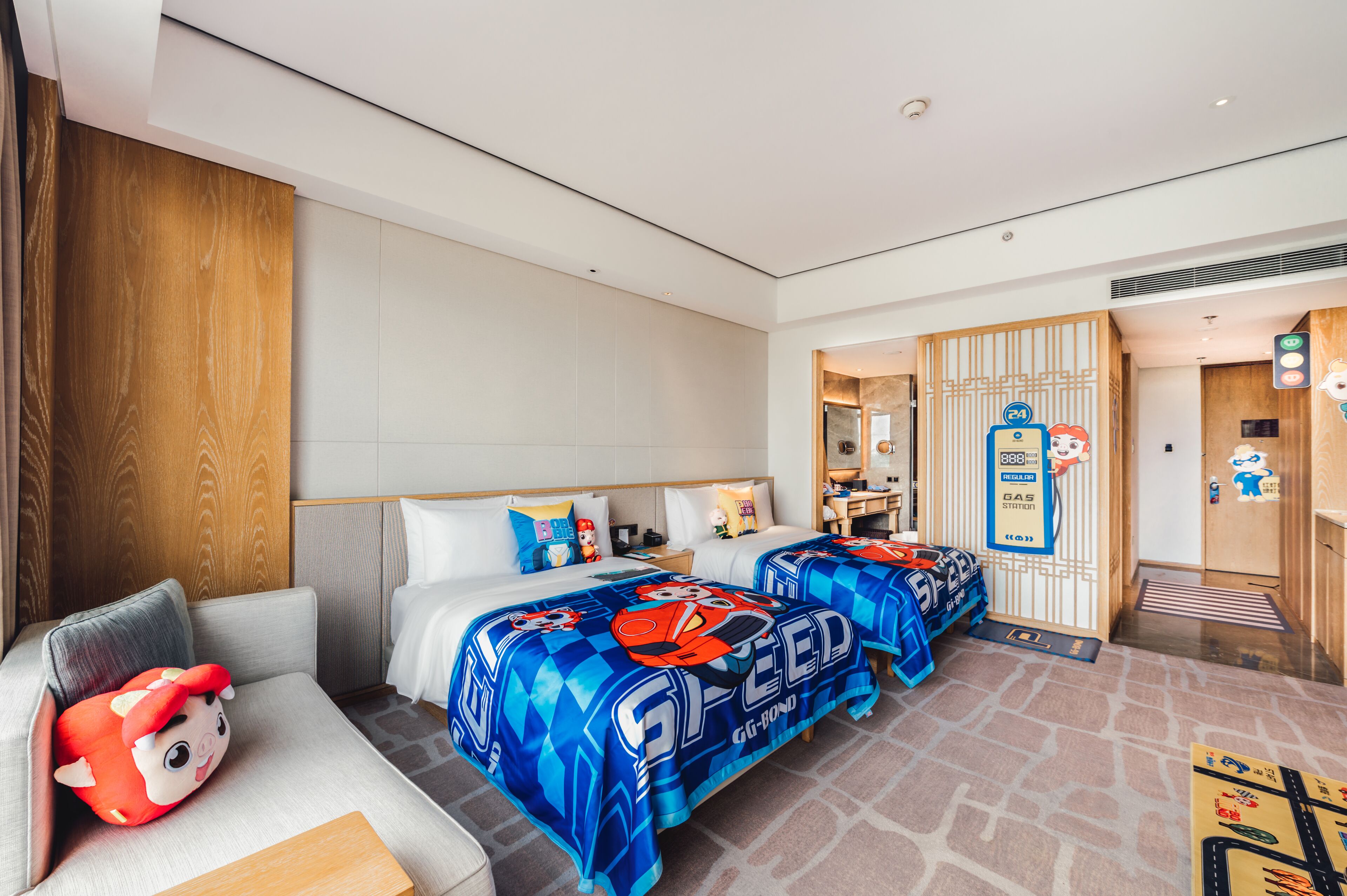 Une chambre d’hôtel avec deux lits, un canapé et un jouet en peluche.