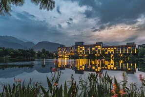 Un hotel moderno con una piscina reflectante y vistas a la montaña.