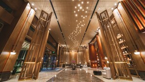 A spacious lobby with a high ceiling, polished marble floors, and modern wooden paneling. - Le Méridien Emei Mountain Resort (Leshan)