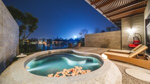 A hot tub with a curved edge, surrounded by a stone wall and a wooden pergola. - Le Méridien Emei Mountain Resort (Leshan)