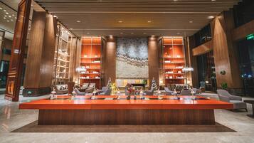A spacious lobby with a central reception desk, high ceilings, and modern lighting.