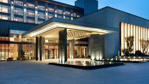 A modern hotel entrance with a covered lobby, large columns, and a water feature. - Le Méridien Emei Mountain Resort (Leshan)