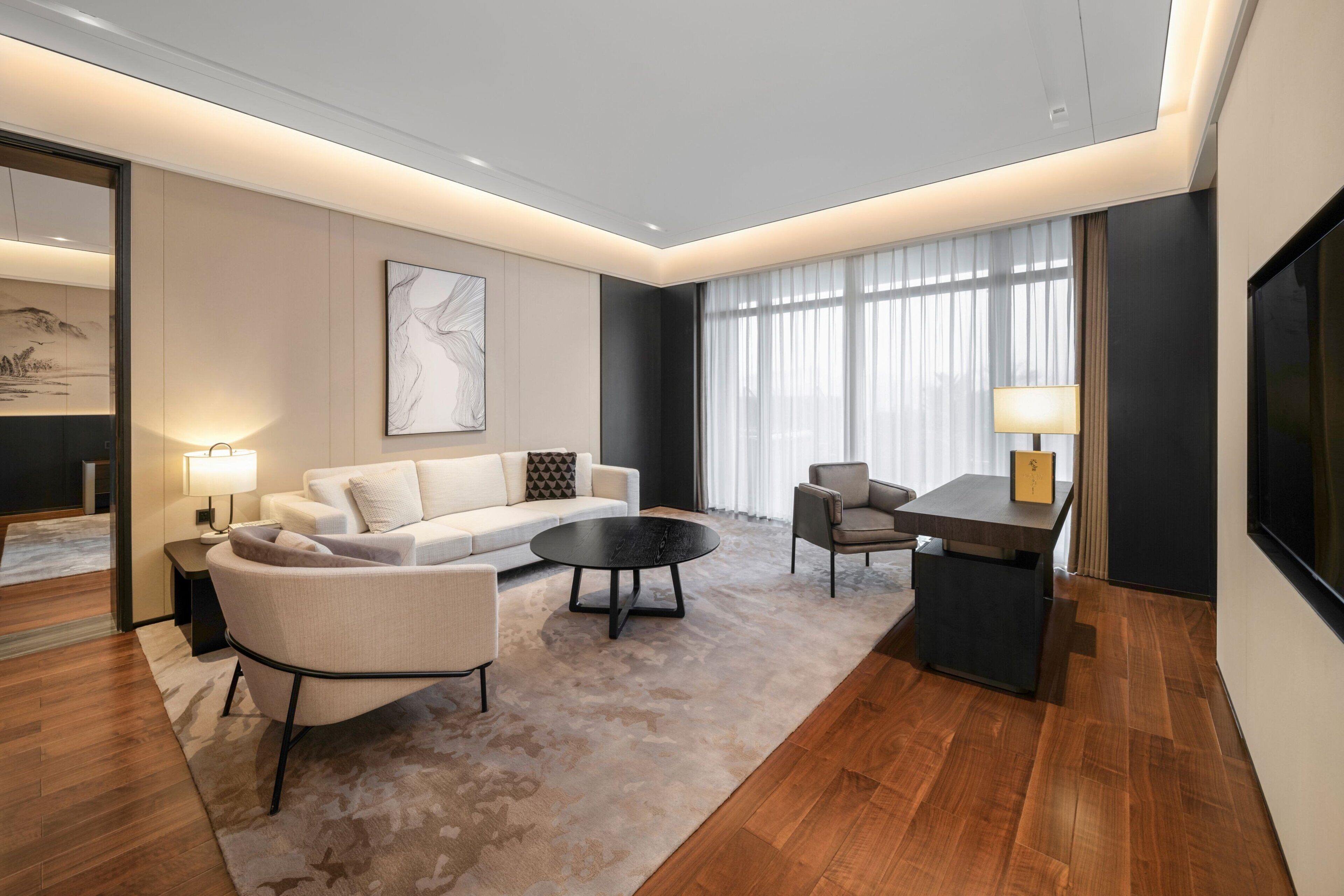 A modern living room with a sofa, armchairs, a coffee table, and a TV.