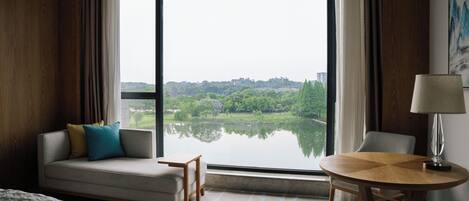 Habitación de hotel con una ventana grande, un sofá, una mesita y una lámpara.