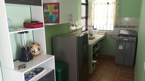 Una cocina compacta con refrigerador, lavamanos y estufa.