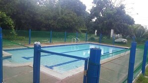 Una piscina rectangular con una cerca azul y una barrera de seguridad con red.