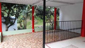 A covered outdoor area with a patterned floor, a metal gate, and red pillars.