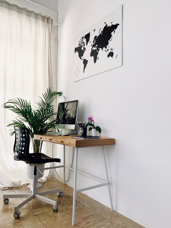 A workspace with a desk, chair, and a world map on the wall.
