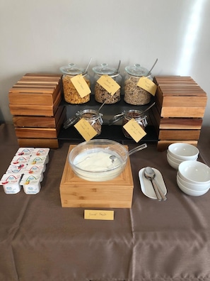 A buffet setup with various food items and containers labeled with names. - Hotel Liane (Riccione)