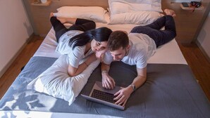 Une chambre à coucher avec un lit, un ordinateur portable et une petite plante posée sur une table de chevet.
