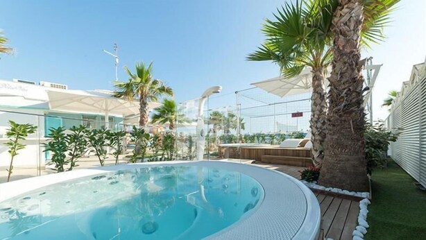 Un bain à remous entouré de palmiers et doté d’une terrasse en bois.