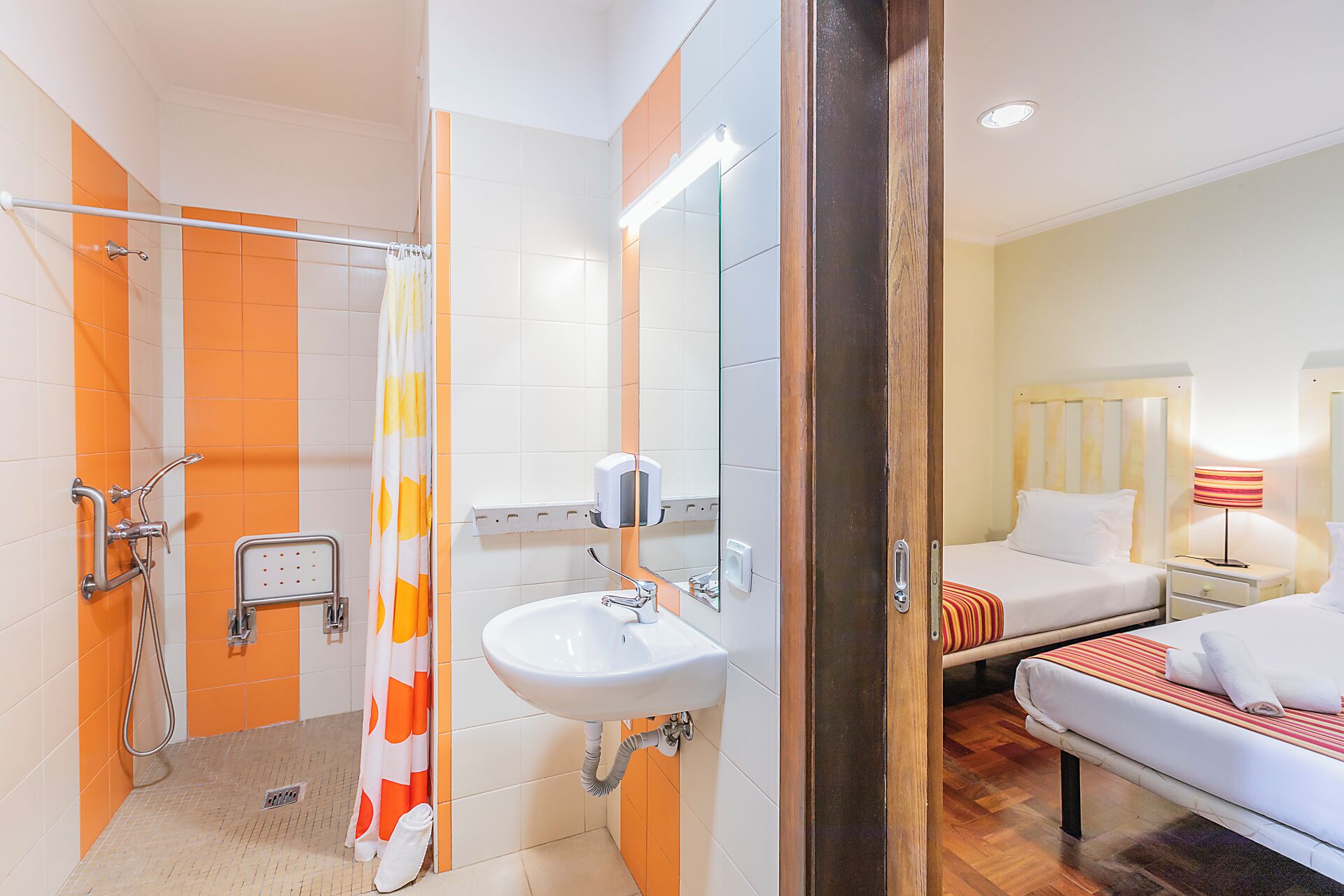 Habitación de hotel con ducha, lavabo y cama.