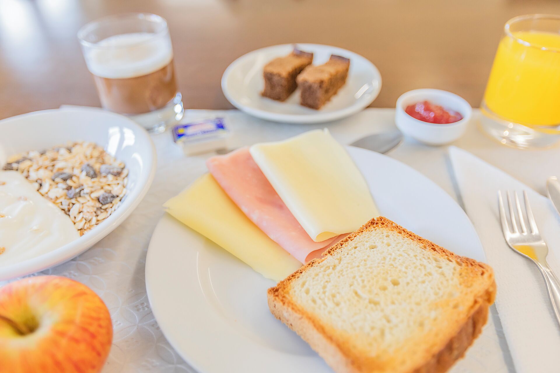 Una colazione con pane tostato, prosciutto, formaggio e un bicchiere di succo d'arancia su un tavolo.