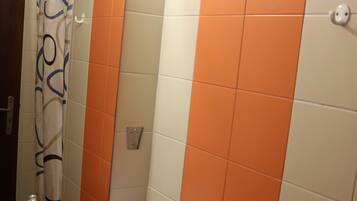 A bathroom with a sink, mirror, and orange-tiled walls.