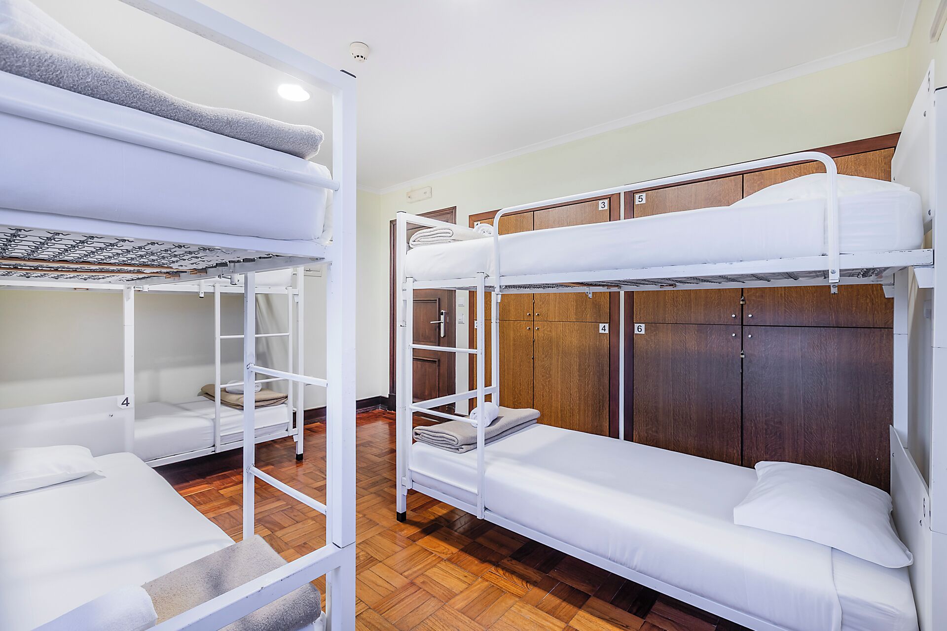 Une chambre de dortoir avec des lits superposés, des armoires en bois et un sol carrelé.