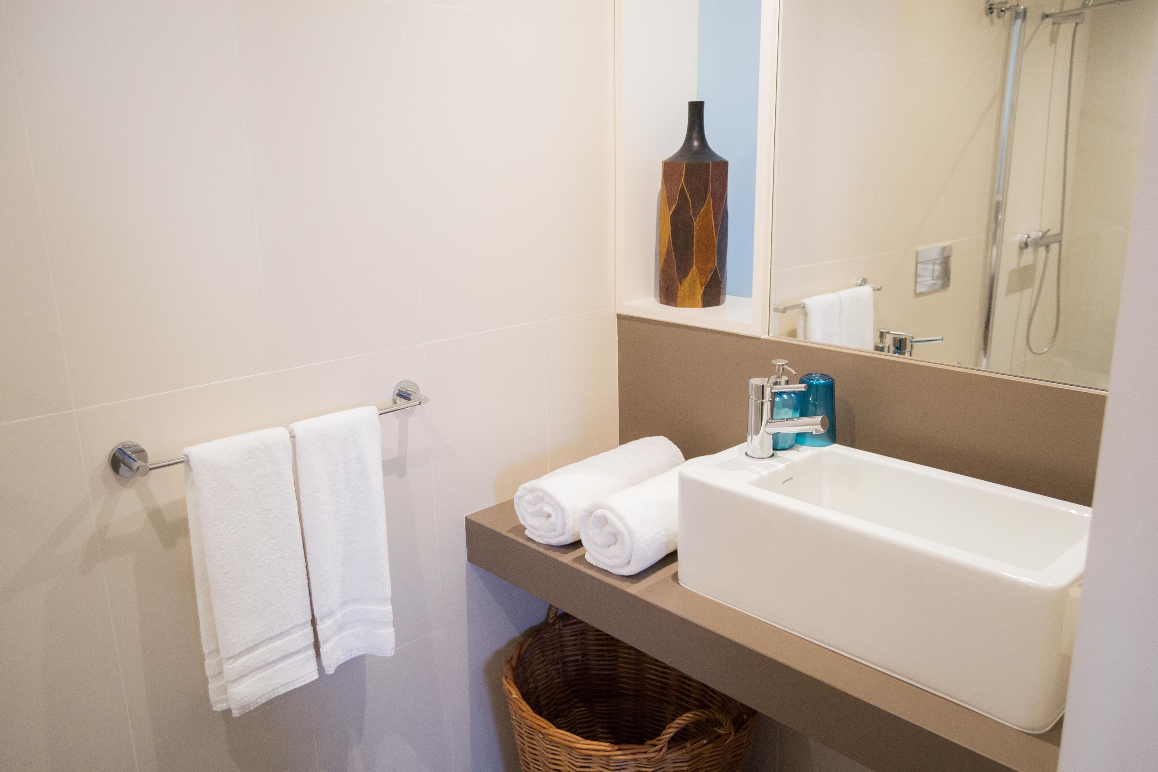 A modern bathroom with a white bathtub, a large mirror, and a towel rack with two white towels.