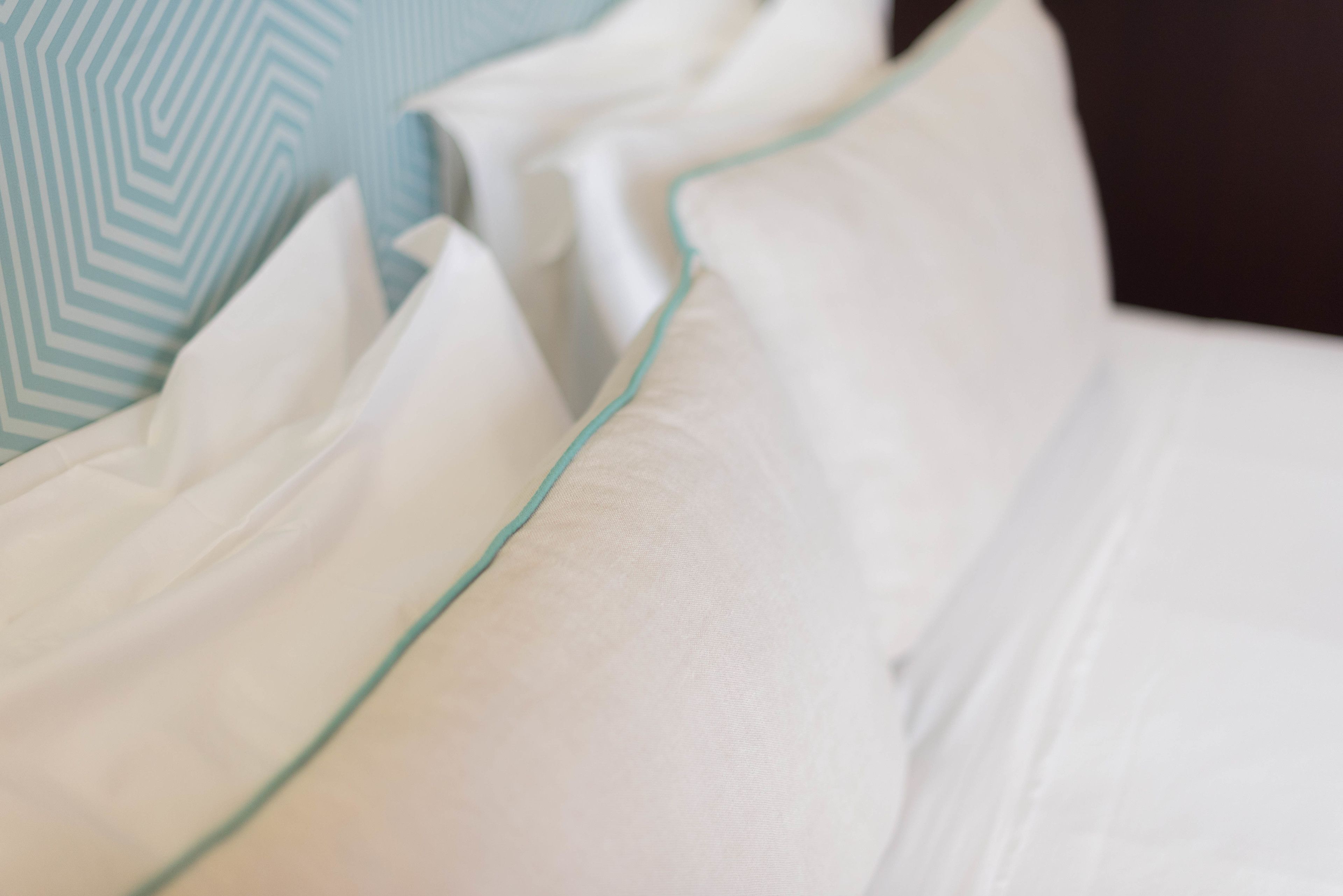 Nahaufnahme von ordentlich arrangierten Kissen mit einem einheitlichen Design, was auf ein gepflegtes und aufgeräumtes Hotelzimmer hindeutet.
