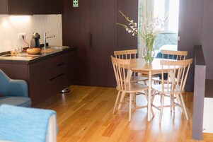 A modern kitchen with wooden cabinets, a built-in oven, and a dining area with a wooden table and chairs.