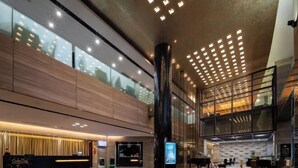 A spacious lobby with a reception desk, a piano, and a large glass wall offering views of the city. - Huaqiao Hotel (Nantong)