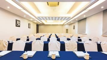 A conference room with rows of tables, chairs, and a ceiling light fixture.