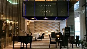 A modern lobby with a grand piano, seating area, and a sign for the lobby bar. - Huaqiao Hotel (Nantong)