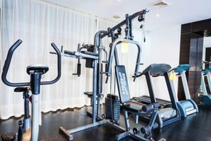 A gym with exercise equipment including a treadmill, elliptical, and weight machines. - Huaqiao Hotel (Nantong)
