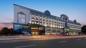 A large hotel with multiple stories, featuring a prominent entrance with arched windows and a large sign. - Huaqiao Hotel (Nantong)