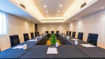 A conference room with a long table, chairs, and a plant.