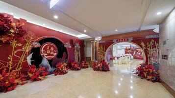 A hotel lobby with a red and gold color scheme, a reception desk, and a decorative archway.