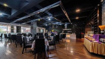 A spacious restaurant with high ceilings, exposed beams, and a variety of seating arrangements.