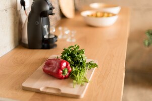 Un plan de travail de cuisine avec un poivron rouge, du persil et une machine à café.