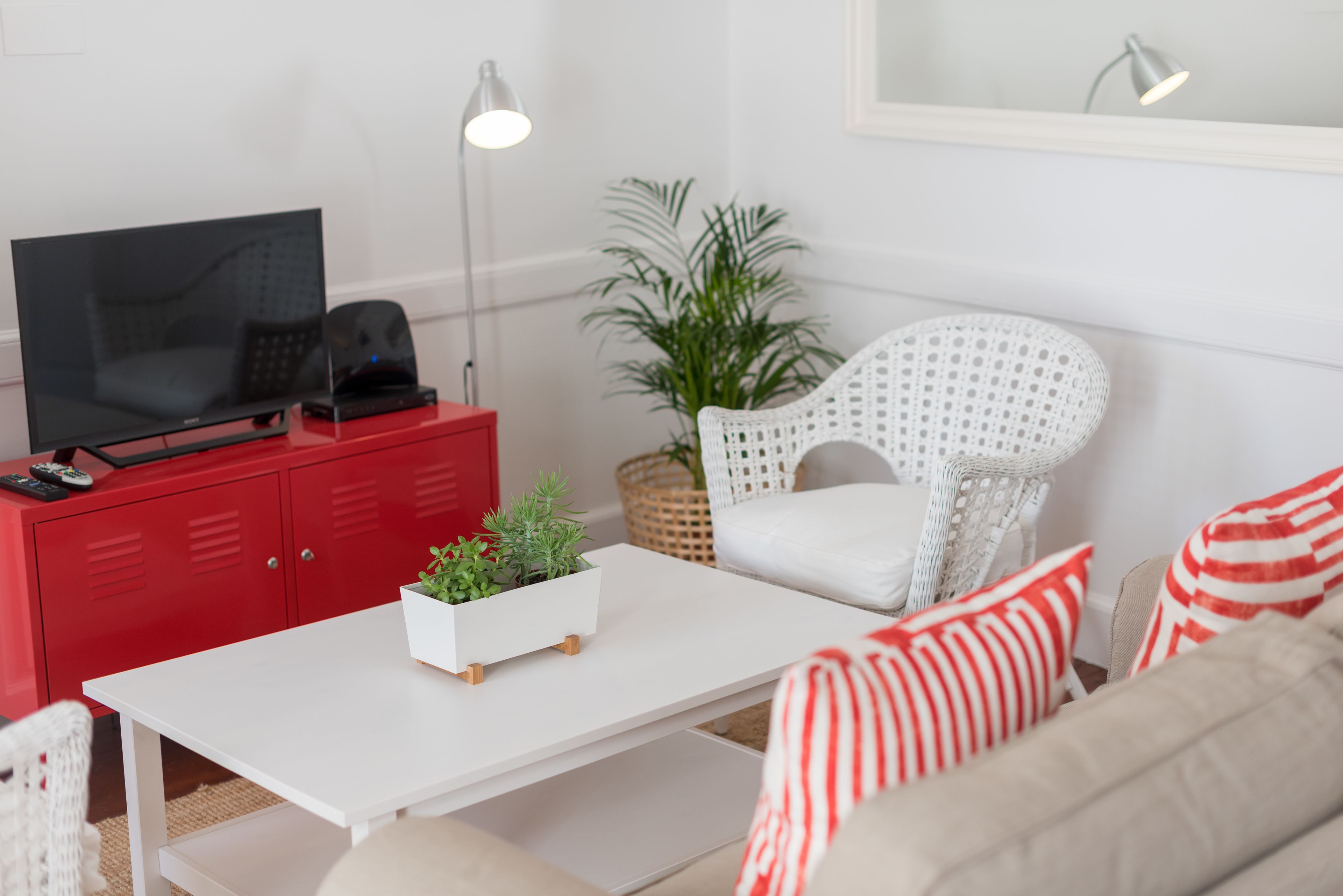 Ein modernes Wohnzimmer mit einem weißen Sofa, einem roten Schrank, einem weißen Couchtisch und einem roten Fernseherkorpus.