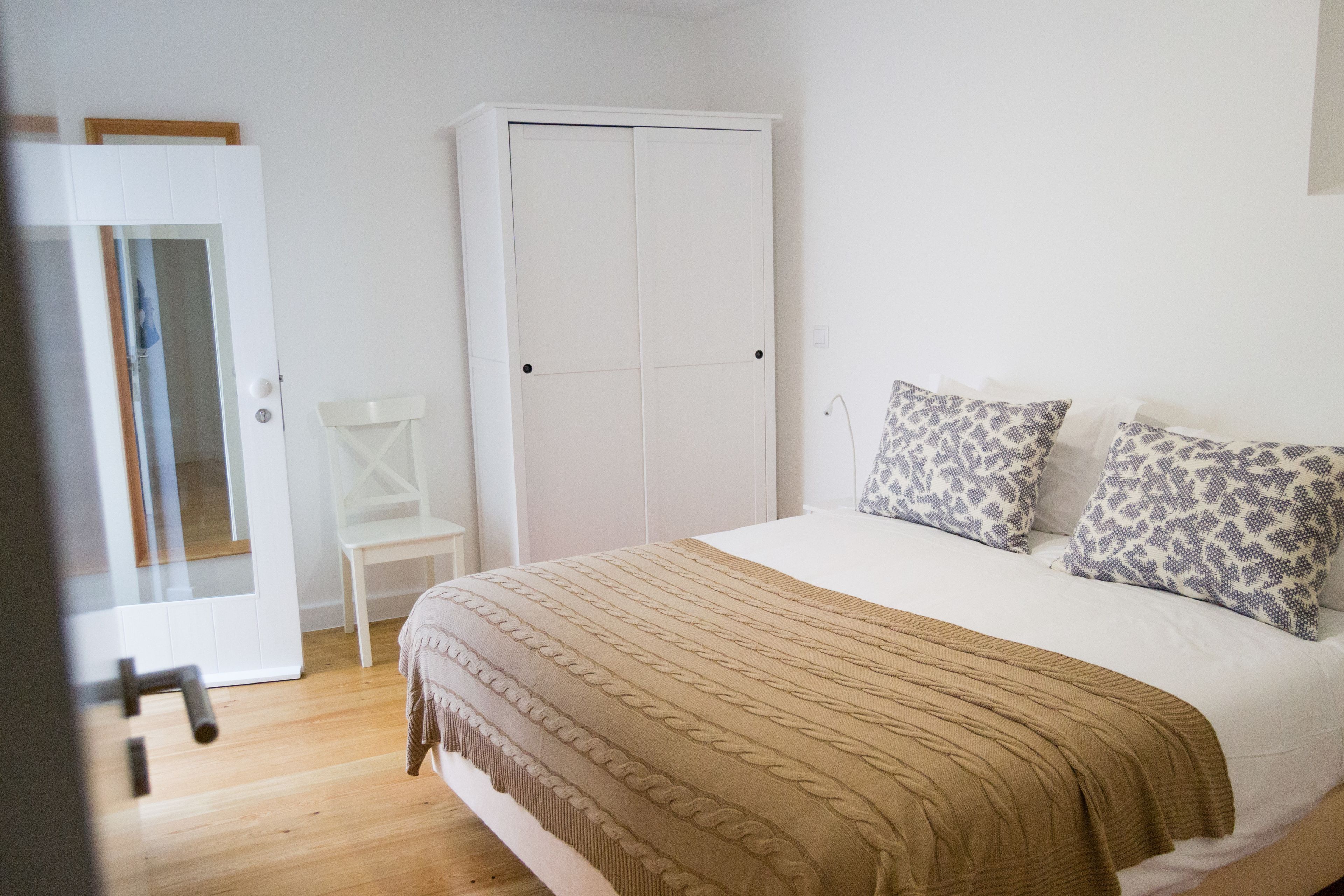 A bedroom with a bed, a wardrobe, and a chair.
