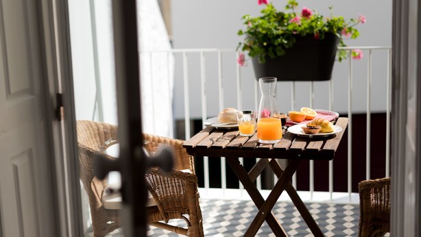 A wooden table with breakfast items and a potted plant on a balcony. - Casa Do Mercado (Funchal)