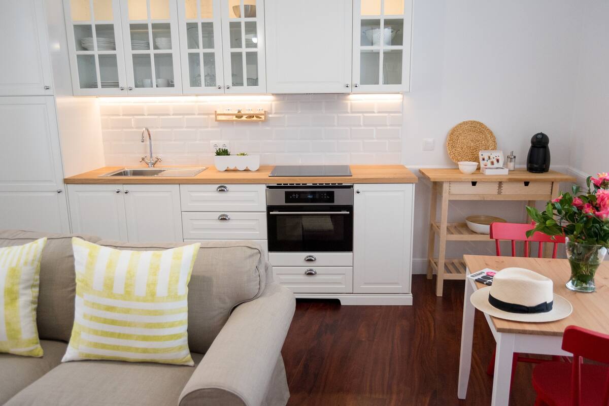 A modern kitchen with white cabinetry, a wooden countertop, and a built-in oven.