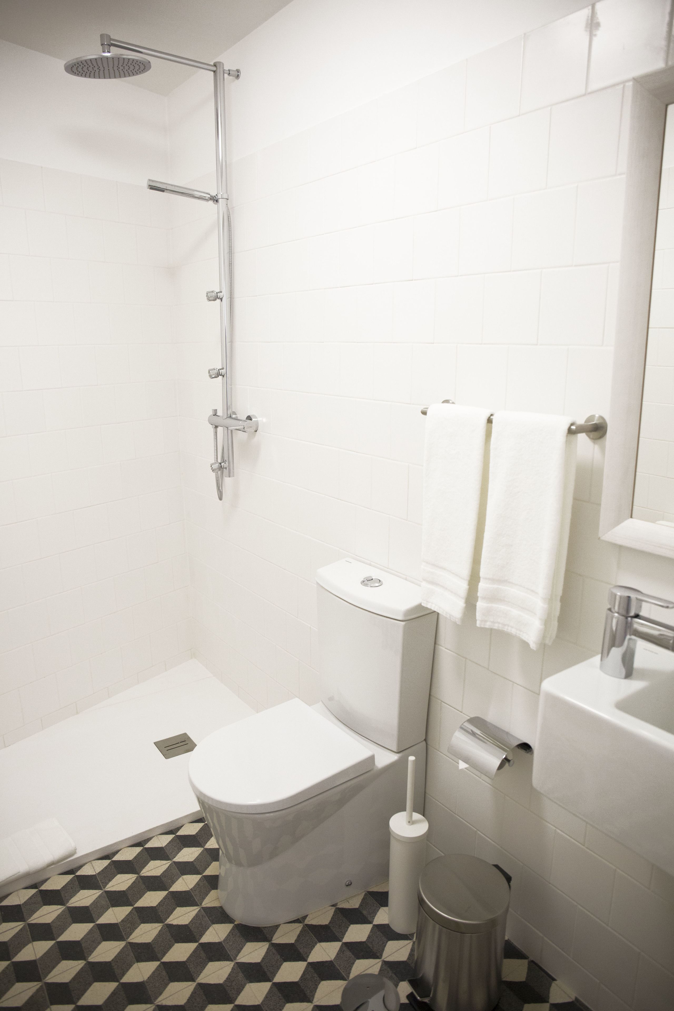 Une salle de bain équipée d’une douche, de toilettes, d’un lavabo et d’une poubelle.