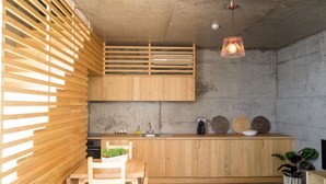 A modern kitchen with wooden cabinetry, a built-in stove, and a hanging pendant light. - Casa Do Mercado (Funchal)