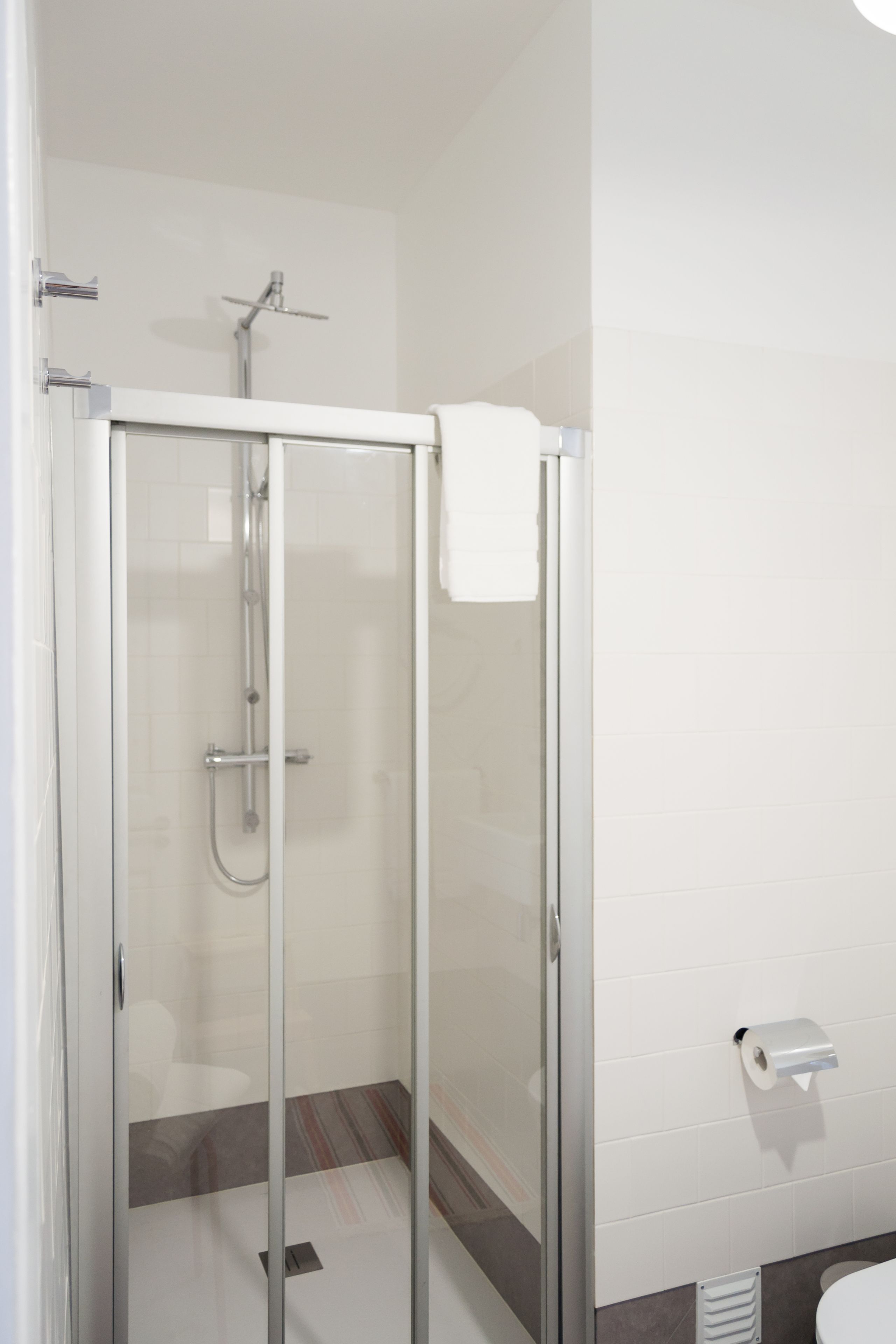 A modern bathroom with a glass-enclosed shower, a toilet, and a towel rack.