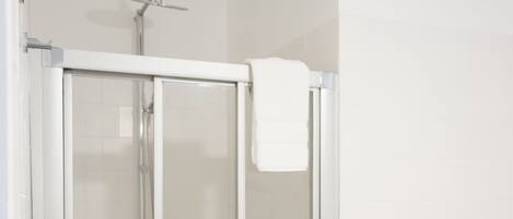 A modern bathroom with a glass-enclosed shower, a toilet, and a towel rack.