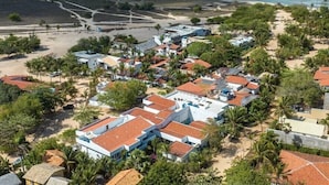 Une station balnéaire dotée de villas en bord de mer, de palmiers et d’une plage de sable.