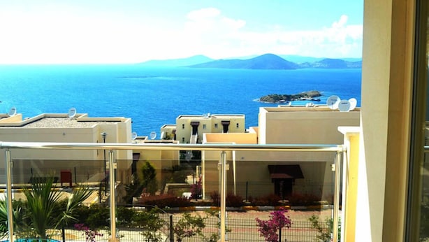 Un balcone con vista sul mare e montagne lontane.