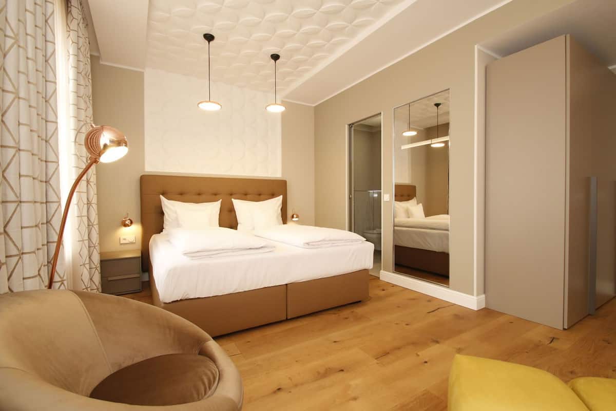 A bedroom with a bed, bedside tables, a chair, a mirror, and a wardrobe.