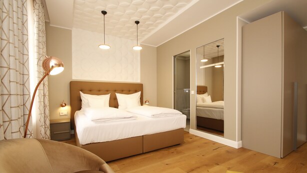 A modern bedroom with a large bed, a chair, and a wardrobe. - Amelie N°1 Hotel & Appartements (Landau in der Pfalz)