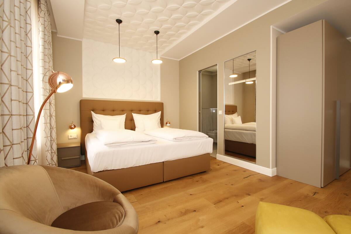 A modern bedroom with a large bed, a chair, and a wardrobe.