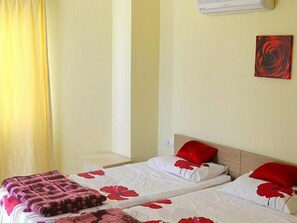 A hotel room with two beds, each with red floral bedding and pillows, a wooden headboard, and a single wall-mounted air conditioner. - 2 Bedroom Apartment Lake View 9 by Likya Global (Milas)
