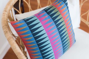 A wicker chair with a colorful, patterned cushion.