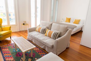 A modern living room with a sofa, a small table, and a colorful rug. - Apartamentos Praça Amarela (Funchal)