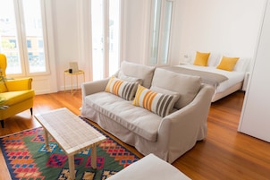 Ein modernes Wohnzimmer mit einer Couch, einem kleinen Tisch und einem farbenfrohen Teppich.