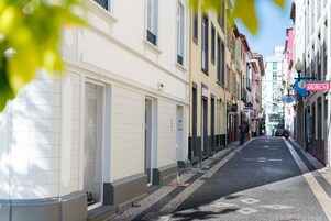 Une rue étroite bordée d’immeubles, dont un restaurant appelé « MURCAS » et une enseigne pour « GUMIL ».
